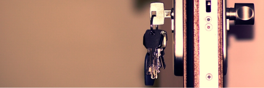 Hand inserting the key into the keyhole of the front door.