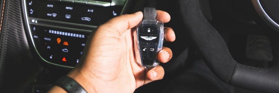 Person inside a car holding a key fob battery